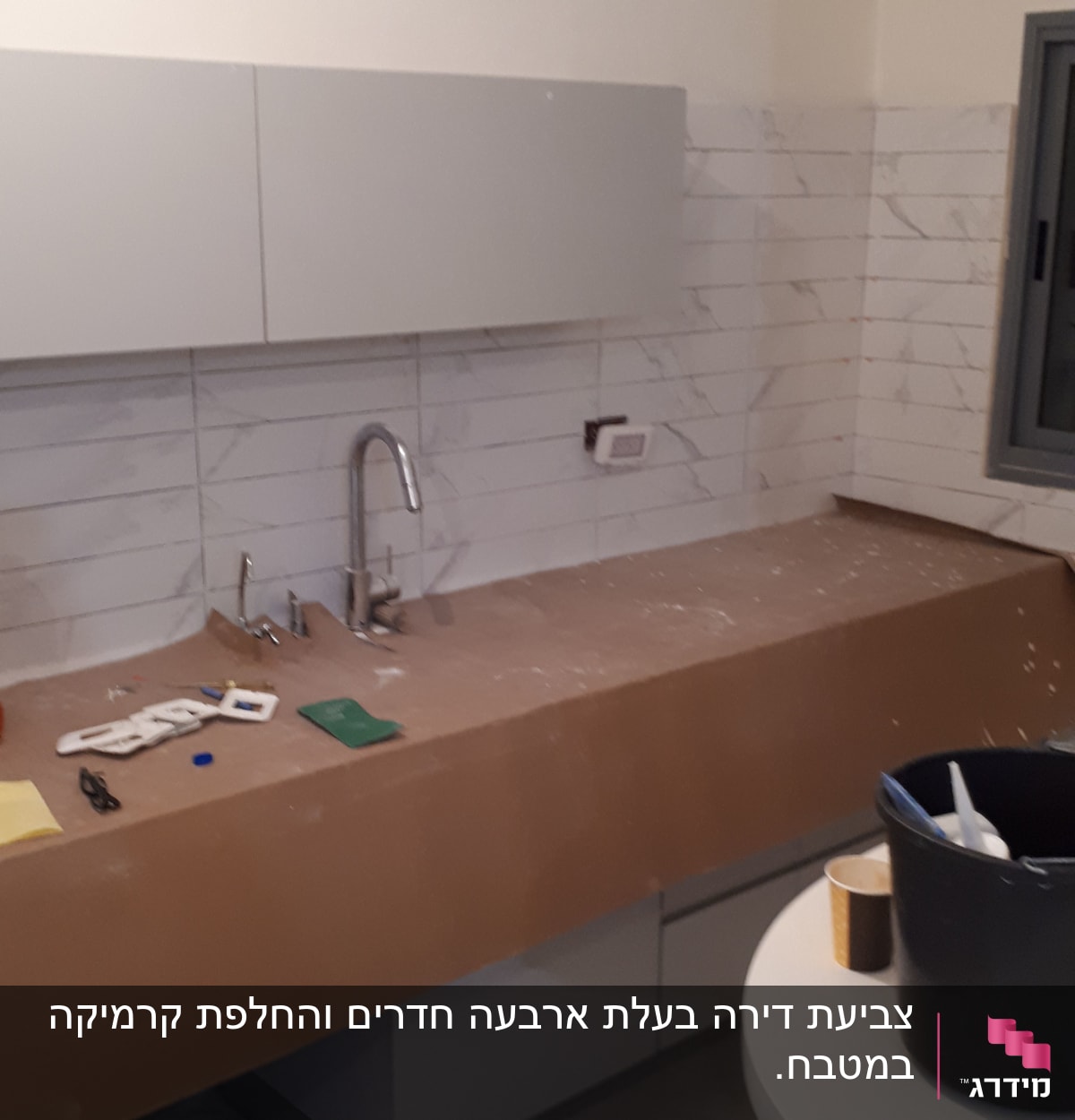 מטבח בשיפוץ עם כיור, ארונות וכלים על השיש